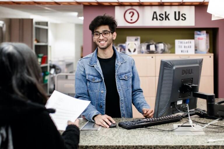 A McMaster student manning the "Ask Us" booth in the library