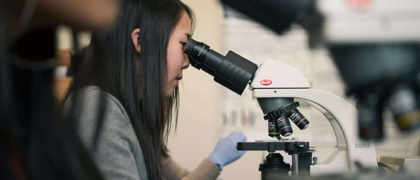 A student peeking into a microscope