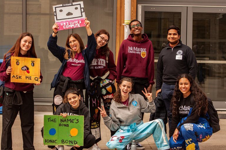 A group of student representatives from different faculties holding up signs