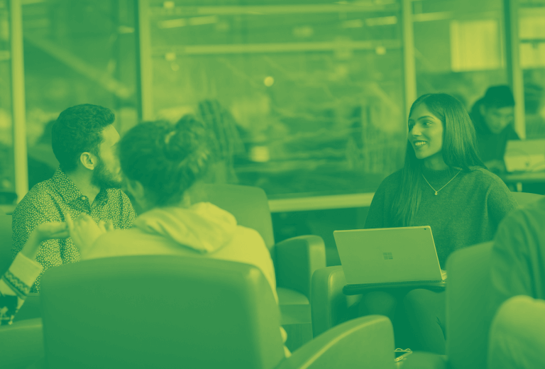 A green duotone image of three students sitting together in a library