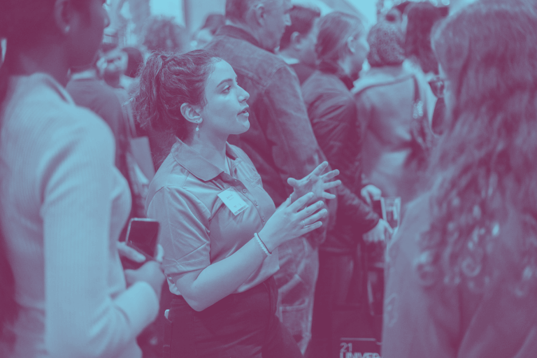 A blue duotone image of a McMaster student representative talking to parents at the Ontario Universities Fair