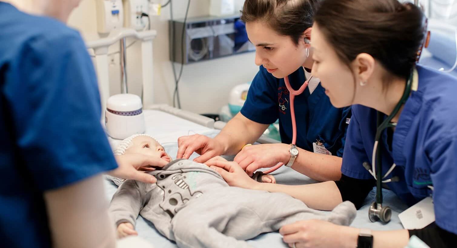 Three nurses examining a baby at the McMaster Children's hospital