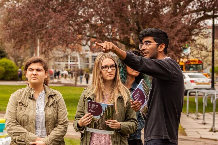 A university student giving directions to three campus visitors