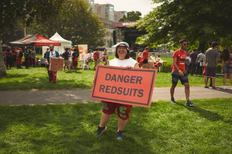McMaster student representative holding a sign reading "Danger redsuits"