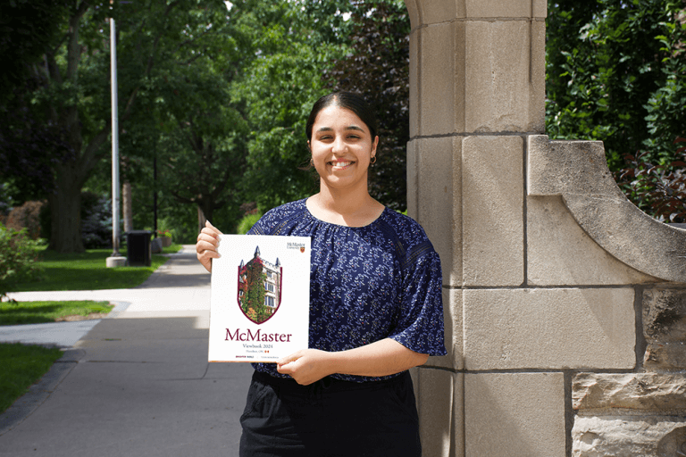 A female McMaster student holding a copy of the lastest 2024 McMaster viewbook.